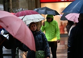 Ciudadanos se protegen con paraguas de la lluvia este lunes por la mañana en una calle de San Sebastián.