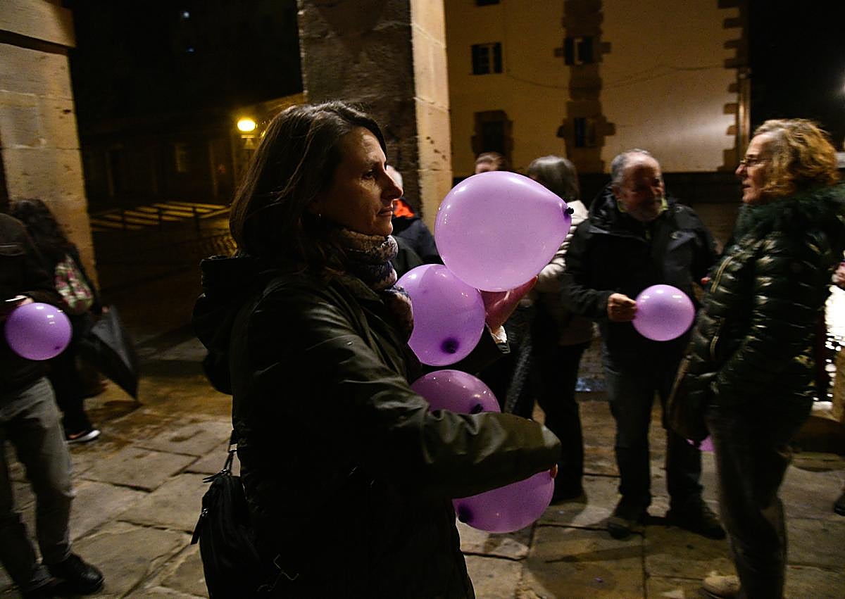 Imagen secundaria 1 - Olatz se dirige a los vecinos que han acudido a arroparla con globos morados por el 25N y que le entregaron un ramo de flores.