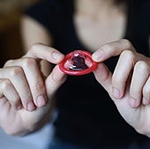 Una mujer sostiene un preservativo entre sus manos.