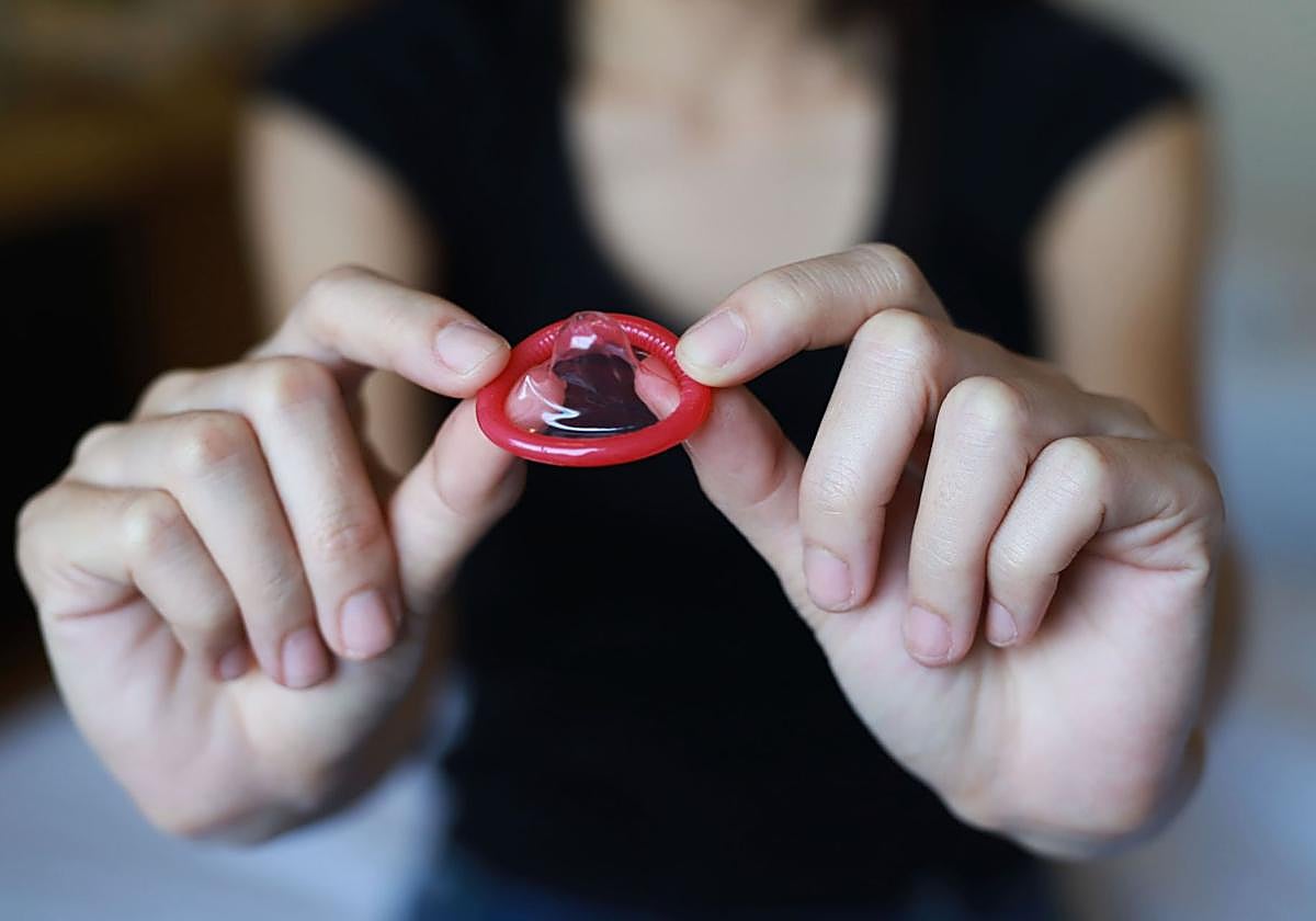 Una mujer sostiene un preservativo entre sus manos.