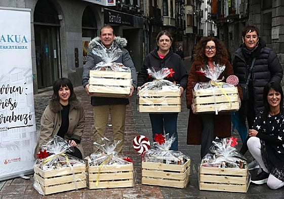 Comerciantes de la localidad posan con las siete cestas que Txankakua sorteará esta Navidad.