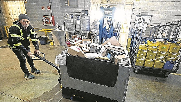 Un operario desplaza una de las cajas con paquetería voluminosa que descargó el trailer.