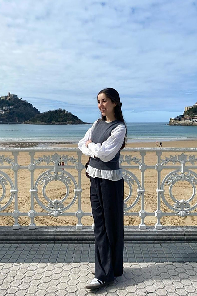 Joven donostiarra con una camisa blanca y chaleco gris, combinándolo con un pantalón de traje azul marino y deportivas.