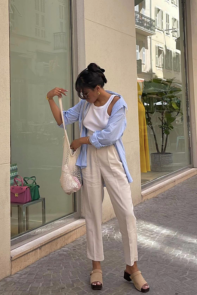 Camisa de lino azul cielo sobre un 'top' básico, pantalón de pinzas crudo y bolso de red.