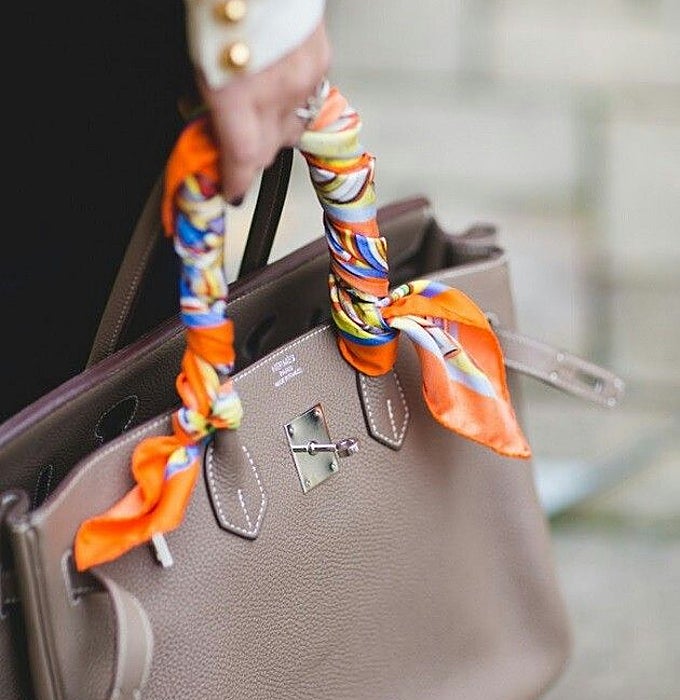 Bolso de cuero con un pañuelo enrollado tipo trenza en las asas.