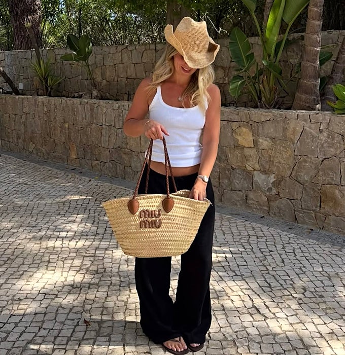 'Top' blanco y pantalones de lino negro con chancletas y bolso de rafia.