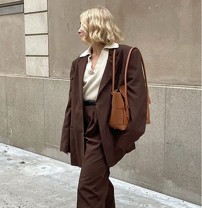 'Blazer' marrón con hombreras con jersey blanco, pantalón de traje y bolso marrón.