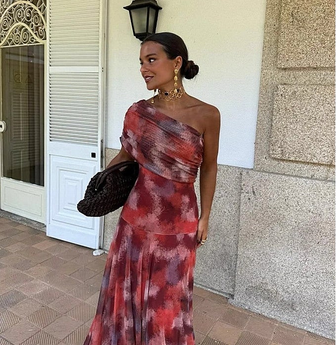 Vestido de estampado 'tie-dye' en tonos rojizos y bolso de rafia trenzada.