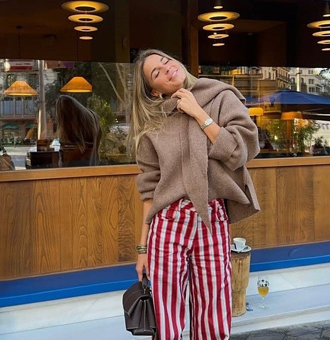 Chaqueta de lana beige, pantalón ancho de rayas verticales en rojo y blanco  y bolso marrón oscuro.