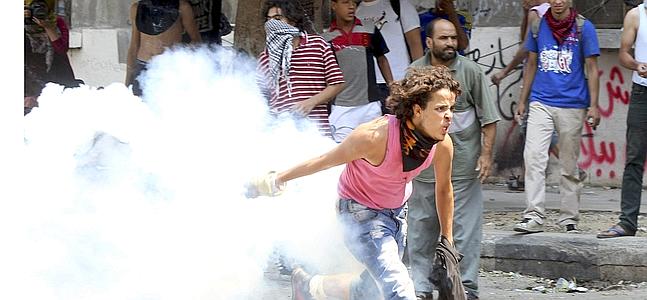 Un manifestante egipcio devuelve una lata de gas lacrimógeno a la Policía. / Khaled Elfiqi (Efe)