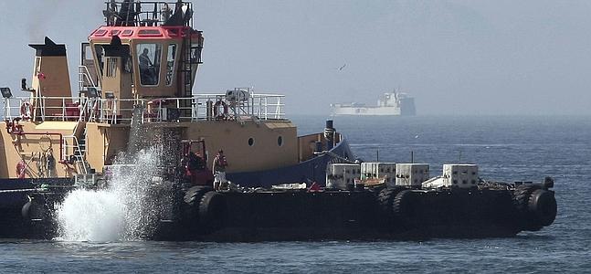 Un remolcador de Gibraltar lanza varios bloques de hormigón al mar. / A. Carrasco (Efe)