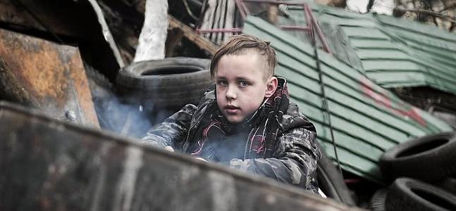 Un niño, tras una barricada en Kiev. / Afp