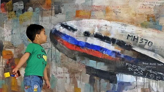 Un niño observa un dibujo del vuelo MH370 de Malaysia Airlines. 