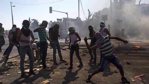 Varios palestinos lanzan piedras durante un enfrentamiento contra las fuerzas israelíes