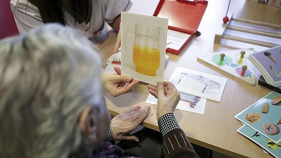 Una anciana examina una fotografía en el Centro de Alzheimer Fundación Reina Sofía. 