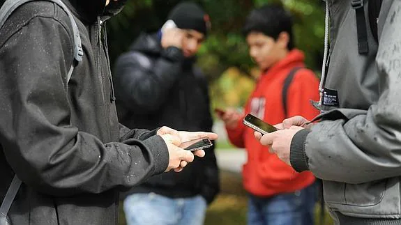 Varios adolescentes utilizan sus teléfonos móviles.
