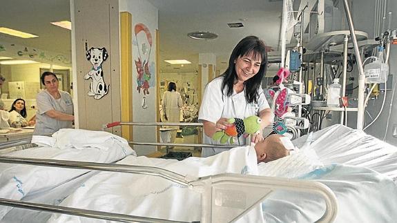 Una enfermera distrae con un peluche a un pequeño ingresado en Cuidados Intensivos de un hospital madrileño.