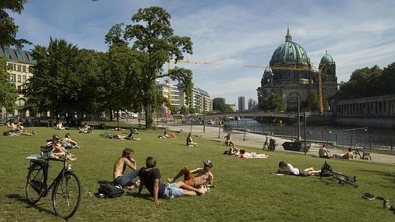 Jóvenes berlineses toman el sol en un parque. 