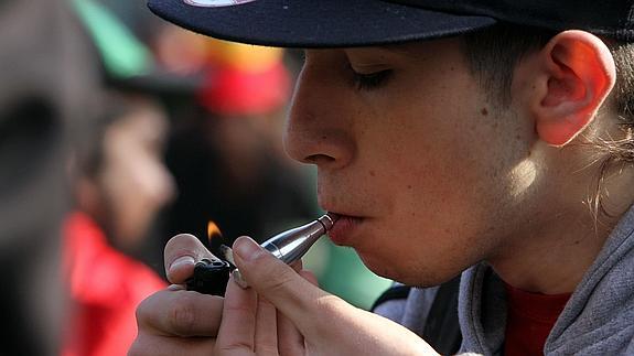Un joven enciende un cigarrillo de marihuana.