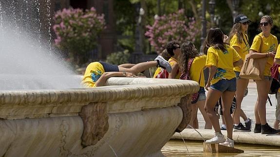 Un grupo de estudiantes se refresca en una fuente sevillana. 