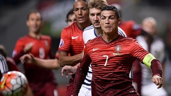 El jugador Cristiano Ronaldo (d) de Portugal en acción con el futbolista Nicklas Bendtner (c) de Dinamarca.