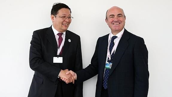 El ministro de Finanzas chino, Lou Jiwei (i) da la mano al ministro de Economía de España, Luis de Guindos (d).
