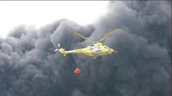 Un helicóptero participa en las labores de extinción. 