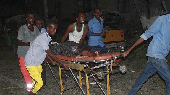 Varias personas transportan a uno de los heridos en el atentado en Mogadiscio.