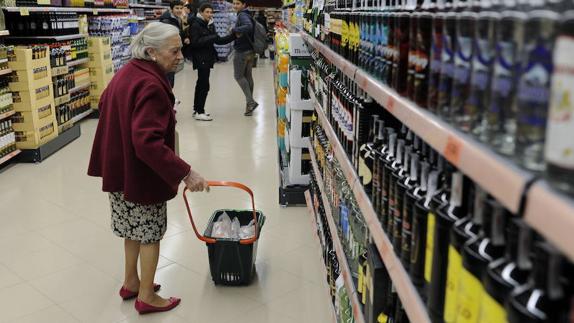 Una mujer, ante la sección de vinos de un supermercado.