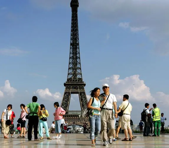 Turistas pasean alrededor de la Torre Eiffel, en París.