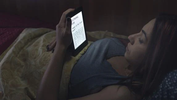 Una joven lee un libro electrónico.
