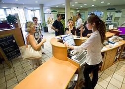 Habitaciones. Una recepcionista del hotel Ibis, ubicado en la avenida de Letxumborro, atiende a varios clientes . ::                             F. DE LA HERA