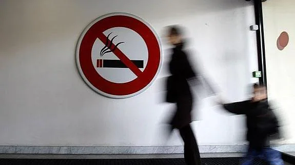 Madre e hjo ante un cartel de 'Prohibido fumar'