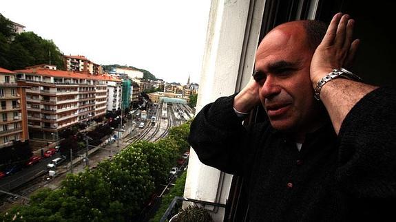 Pablo López, vecino del paseo de Errondo, se tapa los oídos al paso de un tren frente al balcón de su casa