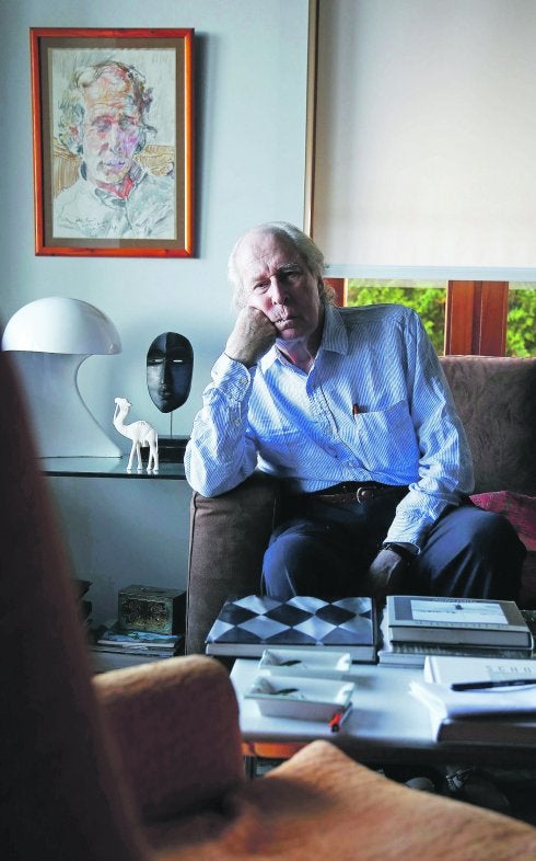 Alberto Schommer posa en su casa donostiarra al lado de un retrato que le pintó su amigo Rafa Ruiz Balerdi.