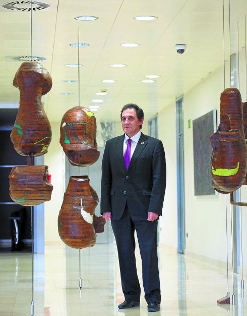 Txomin García posa junto a una obra del artista usurbildarra José Luis Zumeta en la sede central de Laboral Kutxa, en Arrasate.