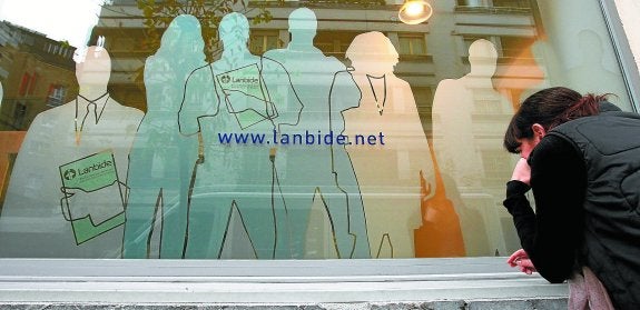 Una joven observa a través de la cristalera de la oficina de Lanbide en el barrio donostiarra de Gros.