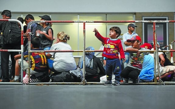 Refugiados sirios esperan en un andén de una estación de trenes. 