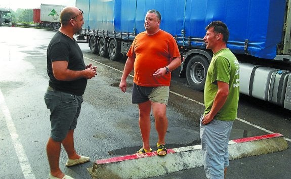El camionero sevillano Juan Antonio Vega conversa con los chóferes rumanos Ionel y Morosan, ayer en el área de servicio de Hernani, en el Segundo Cinturón.