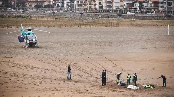 Foto: El cuerpo sin vida del tripulante, cubierto con una sábana sobre la arenade la playa de Zumaia. - Vídeo: Surfistas acuden al rescate de los tripulantes del velero en Zumaia
