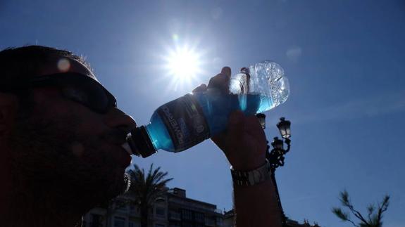 Un hombre bebe en un día de calor. 