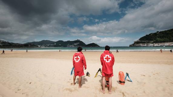 Socorristas en la playa de La Concha en un día nublado. 