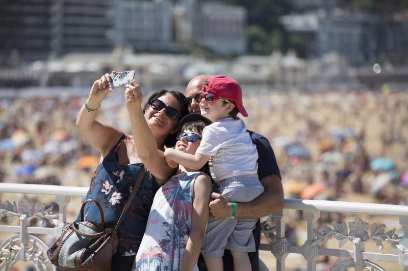 Una familia se fotografía con la playa de La Concha de fondo. 
