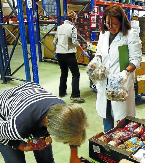 Varios voluntarios preparan lotes de alimentos.