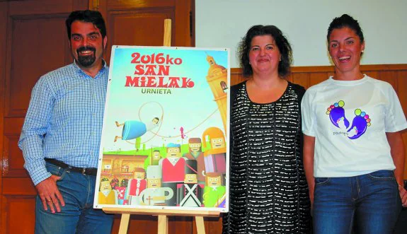 Mikel Pagola, Eva Pérez y María Lesaka junto al cartel anunciador de las fiestas de San Miguel. 