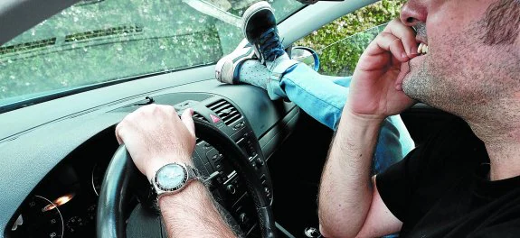 Dos flagrantes infracciones en un mismo vehículo. El conductor se muerde las uñas y su acompañante apoya los pies en el salpicadero.