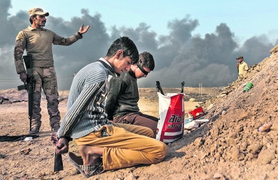 Soldados iraquíes vigilan a dos prisioneros, supuestos componentes del Estado Islámico, al sur de Mosul. 