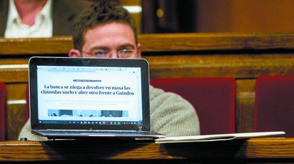 Albano Dante, diputado de Cataluña Si que Es Pot, muestra un titular sobre las cláusulas suelo en el Parlamento catalán. 