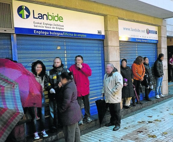 Varias personas aguardan en el exterior de una oficina de Lanbide a que abra sus puertas.