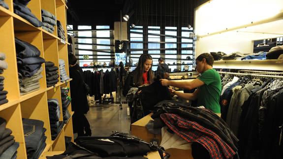Una dependienta ayuda a un cliente en una tienda de ropa.